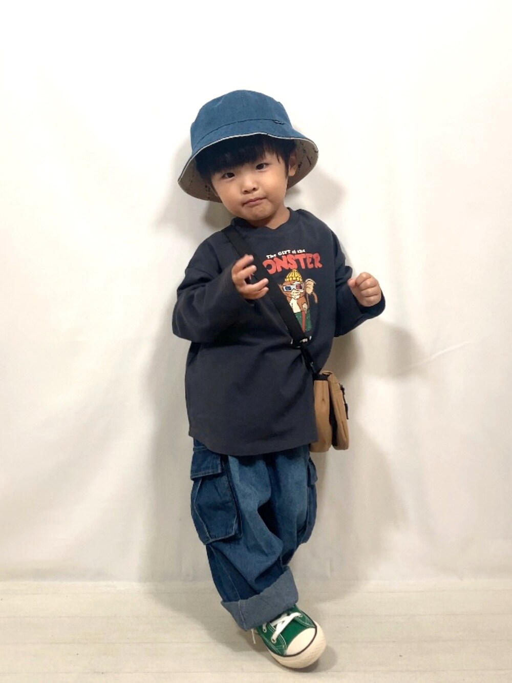 グレー系のトップス、ブルー系のデニムパンツ、イエロー系のショルダーバッグを着用したキッズの秋コーディネートの3枚目の写真