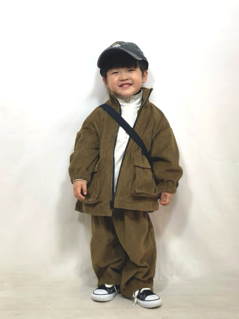 グリーン系のブルゾン、グリーン系のその他パンツ、ブラック系のメッセンジャーバッグを着用したキッズの冬コーディネートの2枚目の写真
