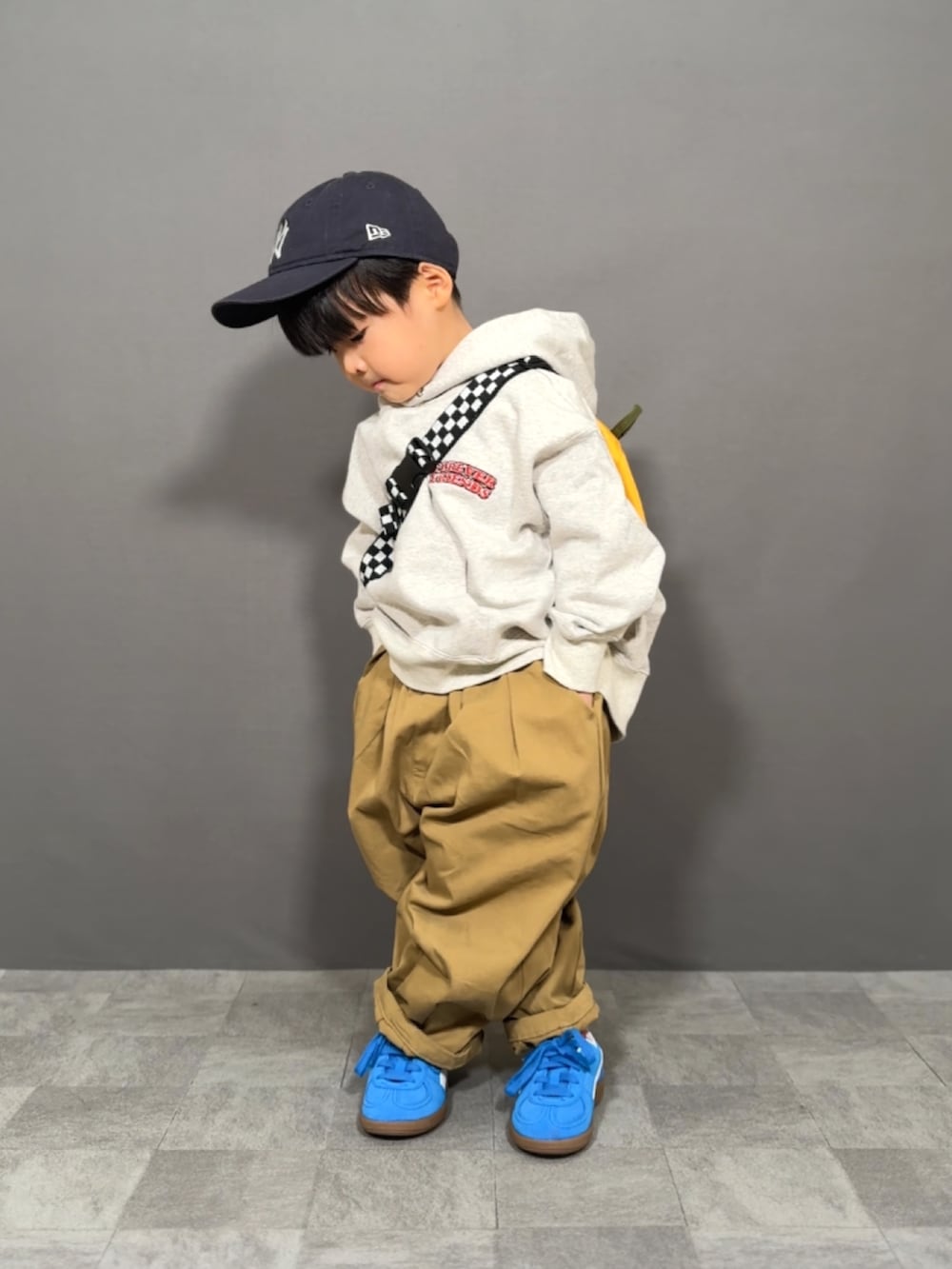 グレー系のスウェット、ブラウン系のその他パンツ、イエロー系のショルダーバッグを着用したキッズの冬コーディネートの4枚目の写真