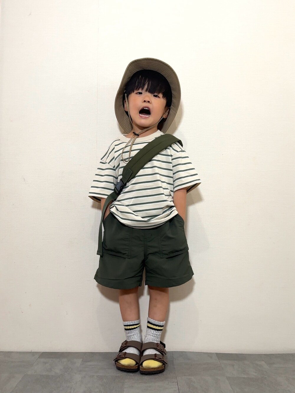 ベージュ系のトップス、イエロー系のパンツ、グリーン系のボディバッグ/ウエストポーチを着用したキッズの夏コーディネートの2枚目の写真