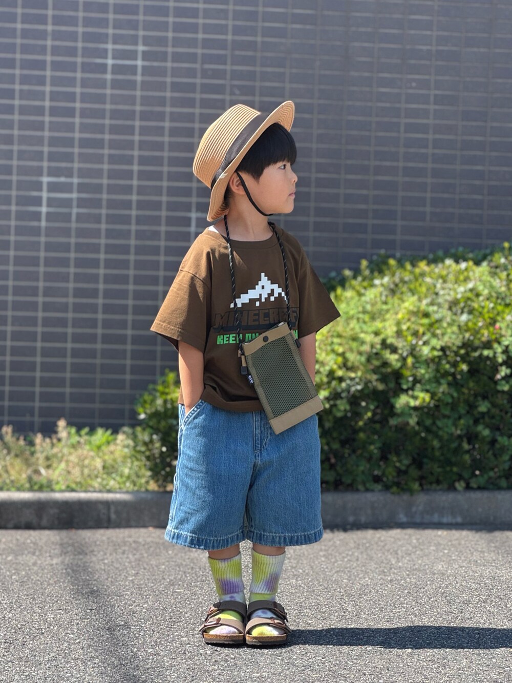 ブラウン系のサンダル、ベージュ系のショルダーバッグ、ブラウン系のTシャツ/カットソーを着用したキッズの夏コーディネートの3枚目の写真