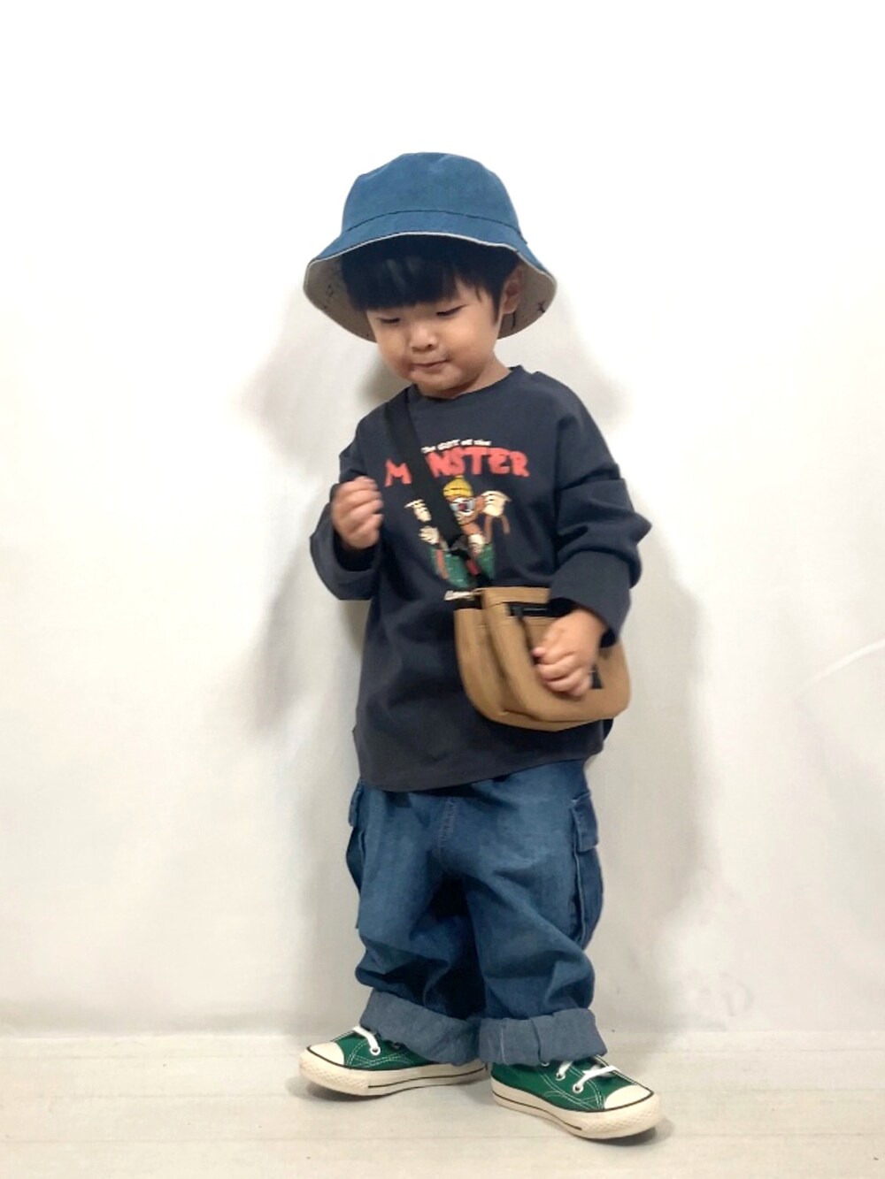 グレー系のトップス、ブルー系のデニムパンツ、イエロー系のショルダーバッグを着用したキッズの秋コーディネートの4枚目の写真