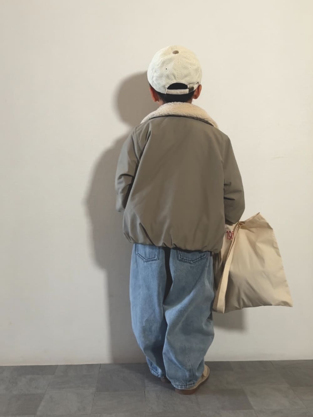 ベージュ系のトートバッグ、ブルー系のTシャツ/カットソー、ベージュ系のモカシン/デッキシューズを着用したキッズの秋コーディネートの3枚目の写真