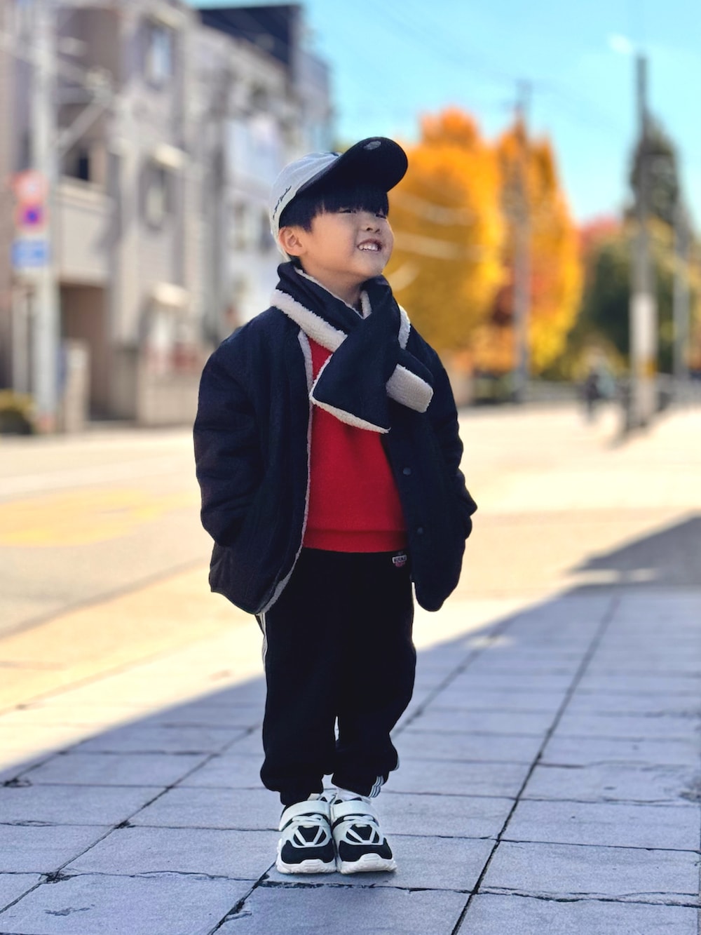 オレンジ系のスウェット、ブラック系のブルゾン、ブラック系のスウェットパンツを着用したキッズの秋コーディネートの2枚目の写真