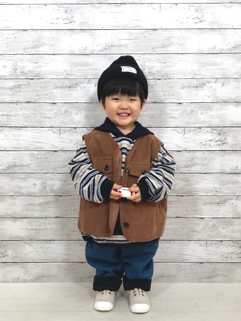 ブラウン系のベスト、ブラック系のパーカー、ブルー系のデニムパンツを着用したキッズの秋コーディネートの2枚目の写真