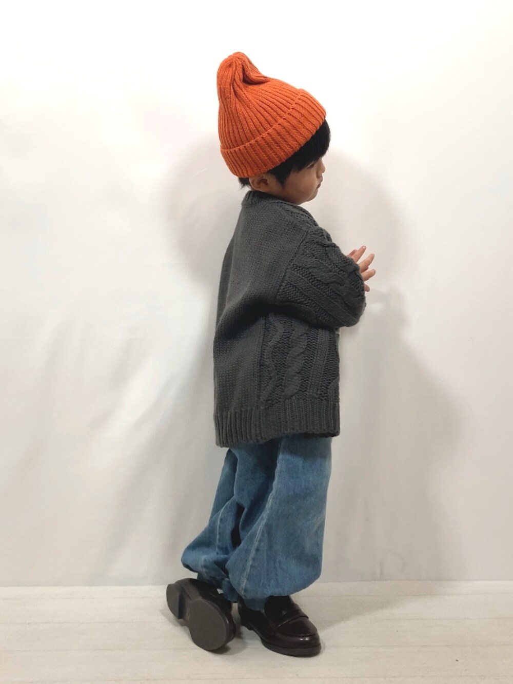 グレー系のカーディガン/ボレロ、グリーン系のTシャツ/カットソー、ブルー系のデニムパンツを着用したキッズの秋コーディネートの5枚目の写真