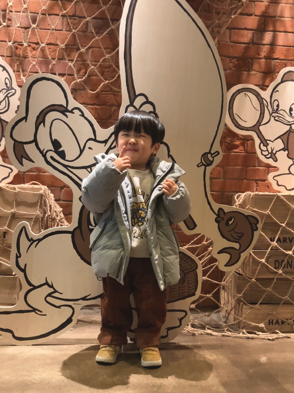 グリーン系のブルゾン、ホワイト系のスウェット、ブラウン系のパンツを着用したキッズの冬コーディネートの2枚目の写真