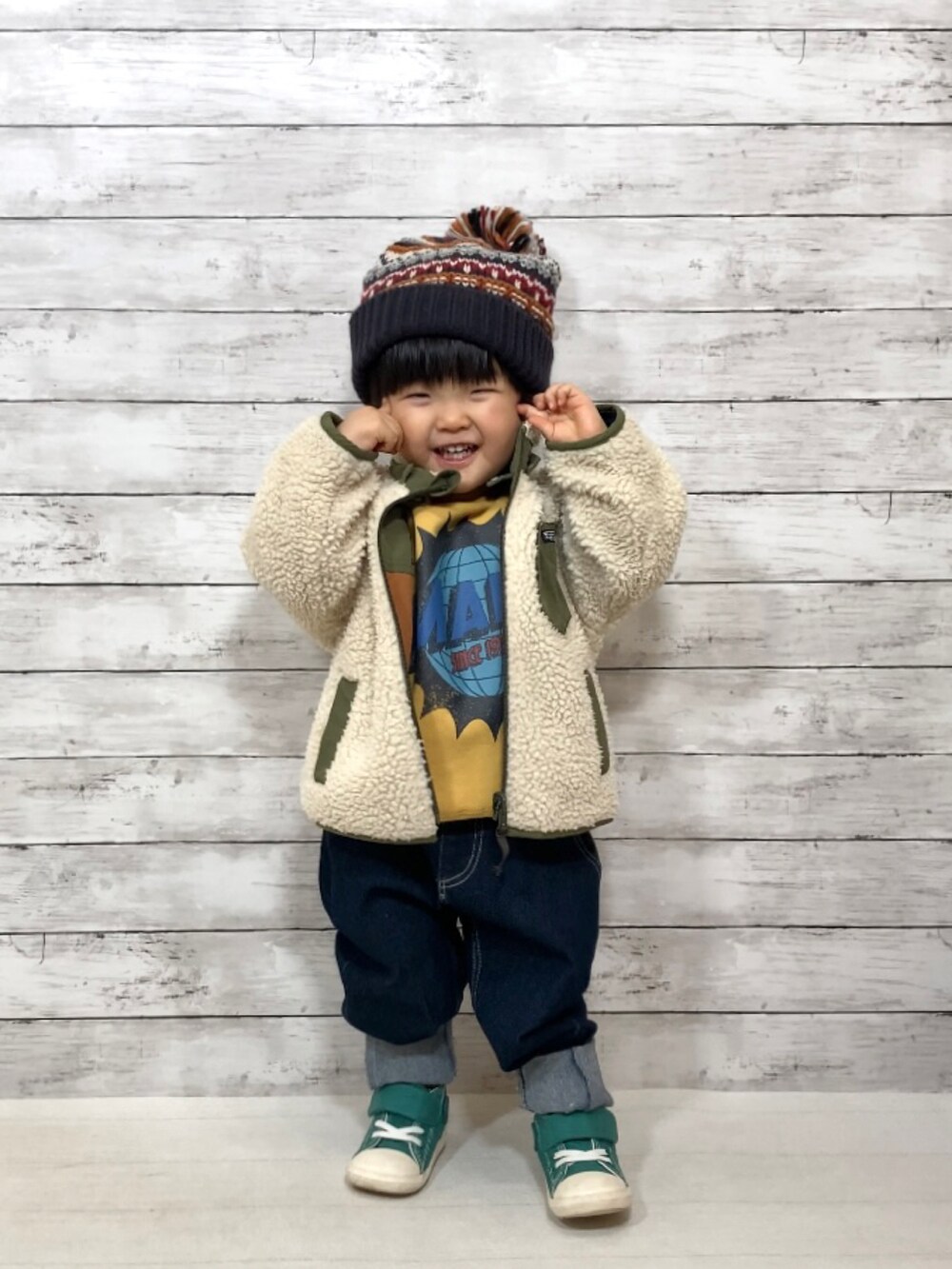 グリーン系のダウンジャケット/コート、イエロー系のスウェット、ブルー系のデニムパンツを着用したキッズの冬コーディネートの2枚目の写真