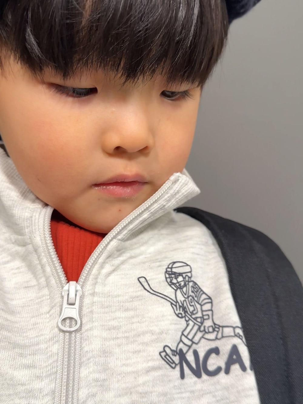 グレー系のスウェット、オレンジ系のTシャツ/カットソー、ブラック系のデニムパンツを着用したキッズの冬コーディネートの5枚目の写真