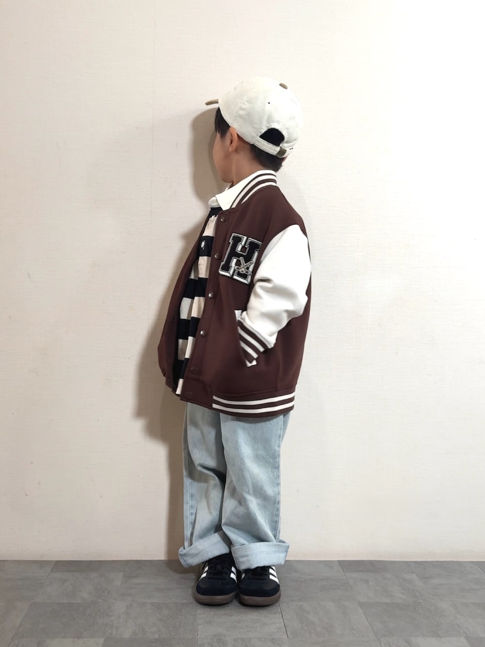 ブラック系のスニーカー、ホワイト系のポロシャツ、ブラウン系のスタジャンを着用したキッズの秋コーディネートの4枚目の写真