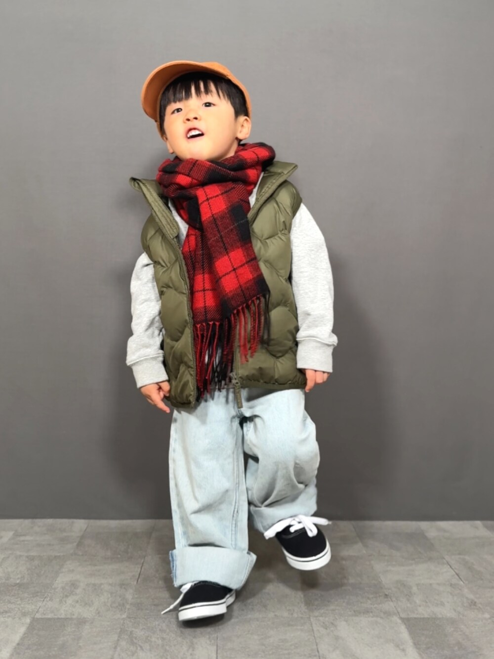 グレー系のスウェット、グリーン系のベスト、ブルー系のデニムパンツを着用したキッズの冬コーディネートの3枚目の写真