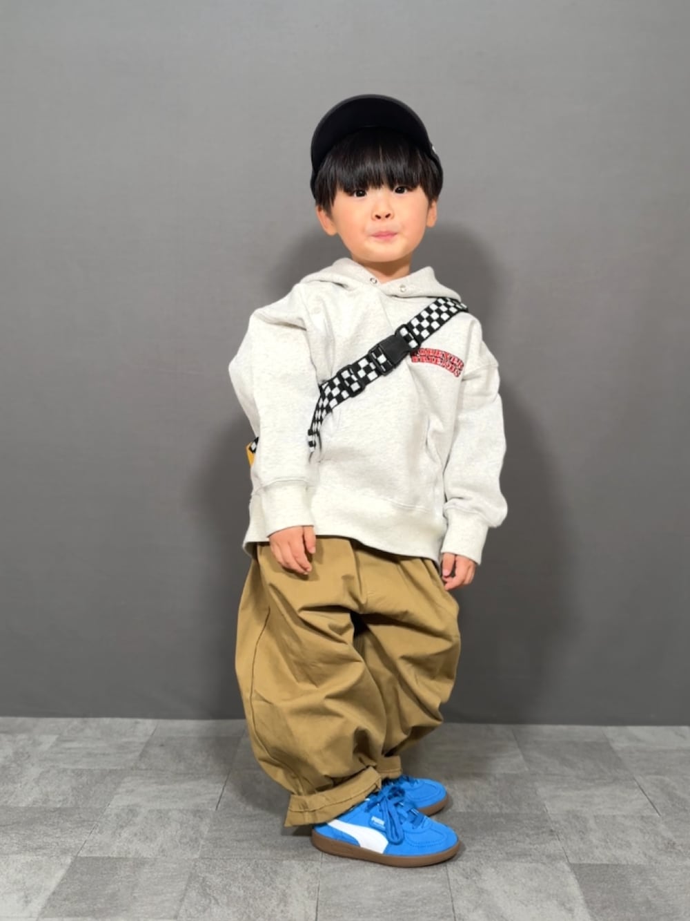 グレー系のスウェット、ブラウン系のその他パンツ、イエロー系のショルダーバッグを着用したキッズの冬コーディネートの2枚目の写真