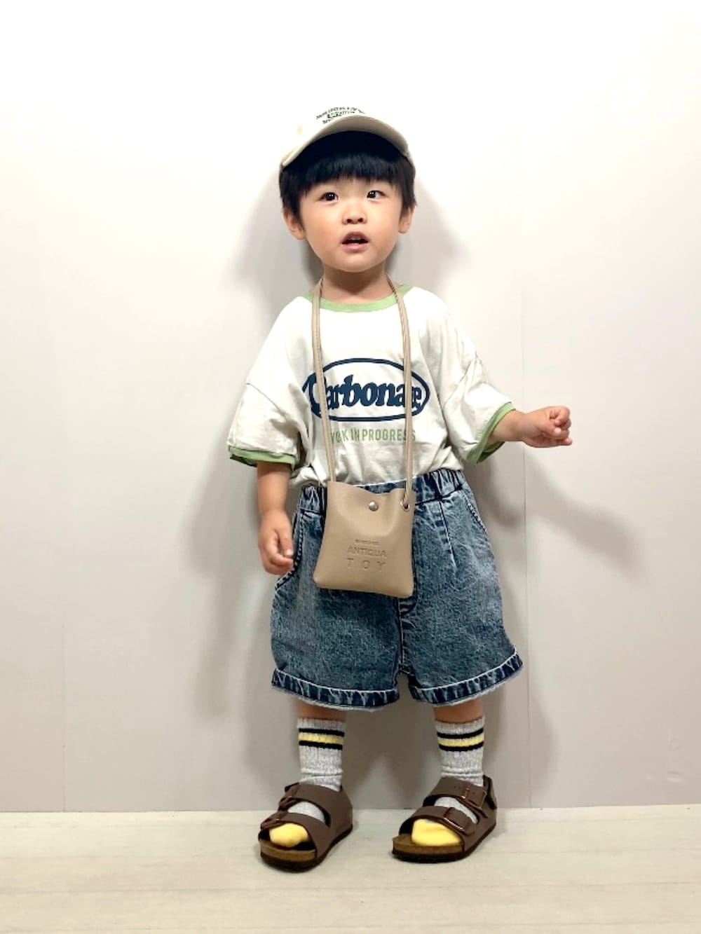 グレー系のTシャツ/カットソー、ブルー系のデニムパンツ、ベージュ系のショルダーバッグを着用したキッズの夏コーディネートの2枚目の写真