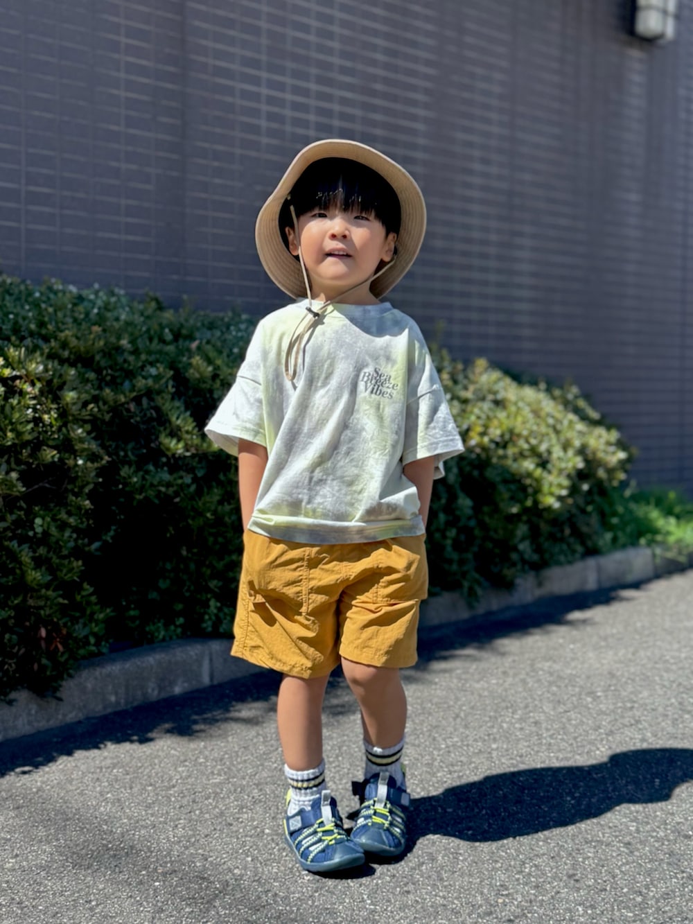 ブルー系のサンダル、グレー系のTシャツ/カットソー、イエロー系のパンツを着用したキッズの夏コーディネートの2枚目の写真