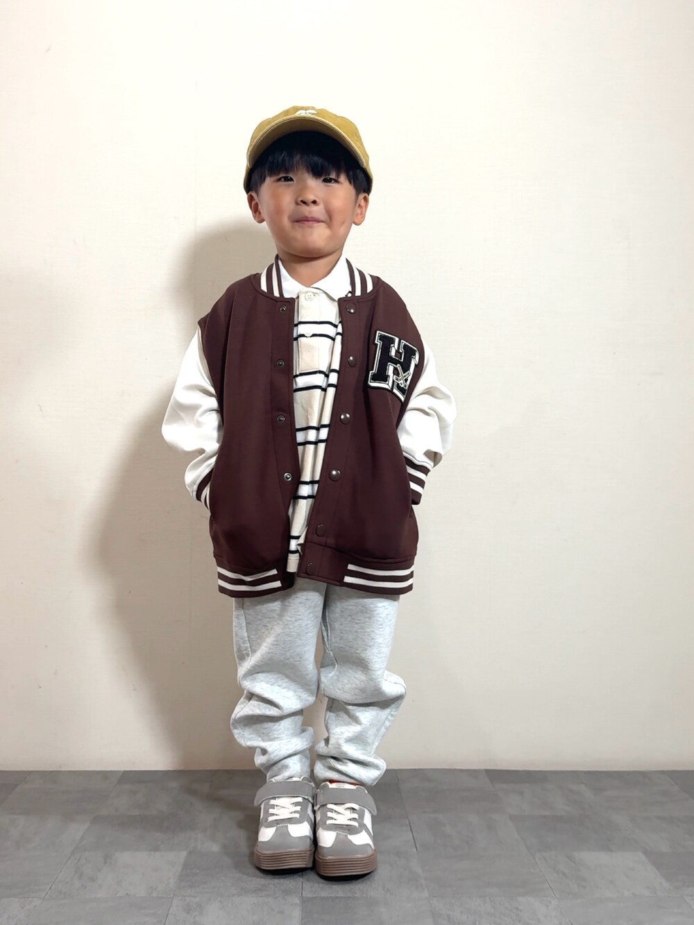 ベージュ系のポロシャツ、ブラウン系のスタジャン、グレー系のスウェットパンツを着用したキッズの夏コーディネートの2枚目の写真