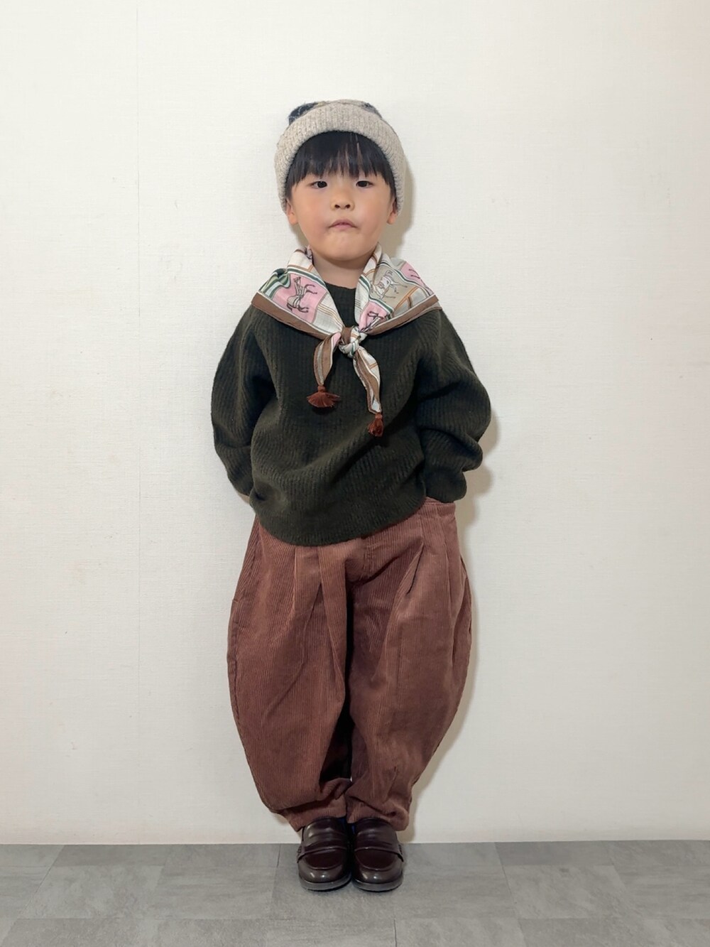 ブラウン系のローファー、ブラウン系のその他パンツ、グリーン系のニット/セーターを着用したキッズの秋コーディネートの2枚目の写真