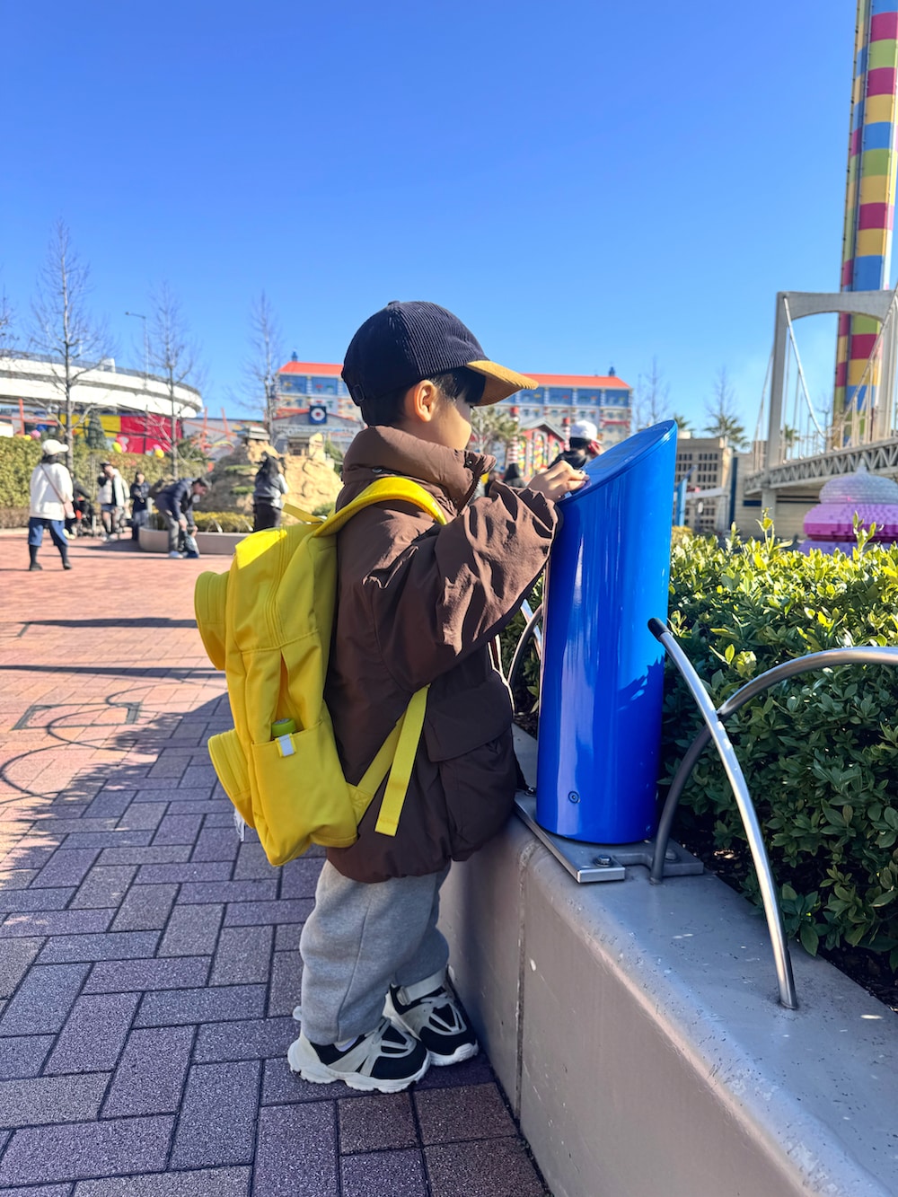 ブラウン系のダウンジャケット/コート、グレー系のスウェットパンツ、イエロー系のバックパック/リュックを着用したキッズの冬コーディネートの4枚目の写真