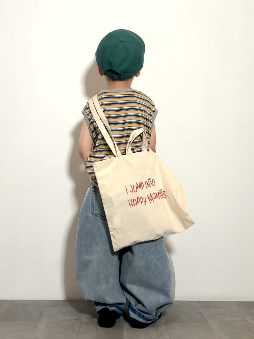 ブルー系のデニムパンツ、ベージュ系のトートバッグ、イエロー系のタンクトップを着用したキッズの夏コーディネートの3枚目の写真