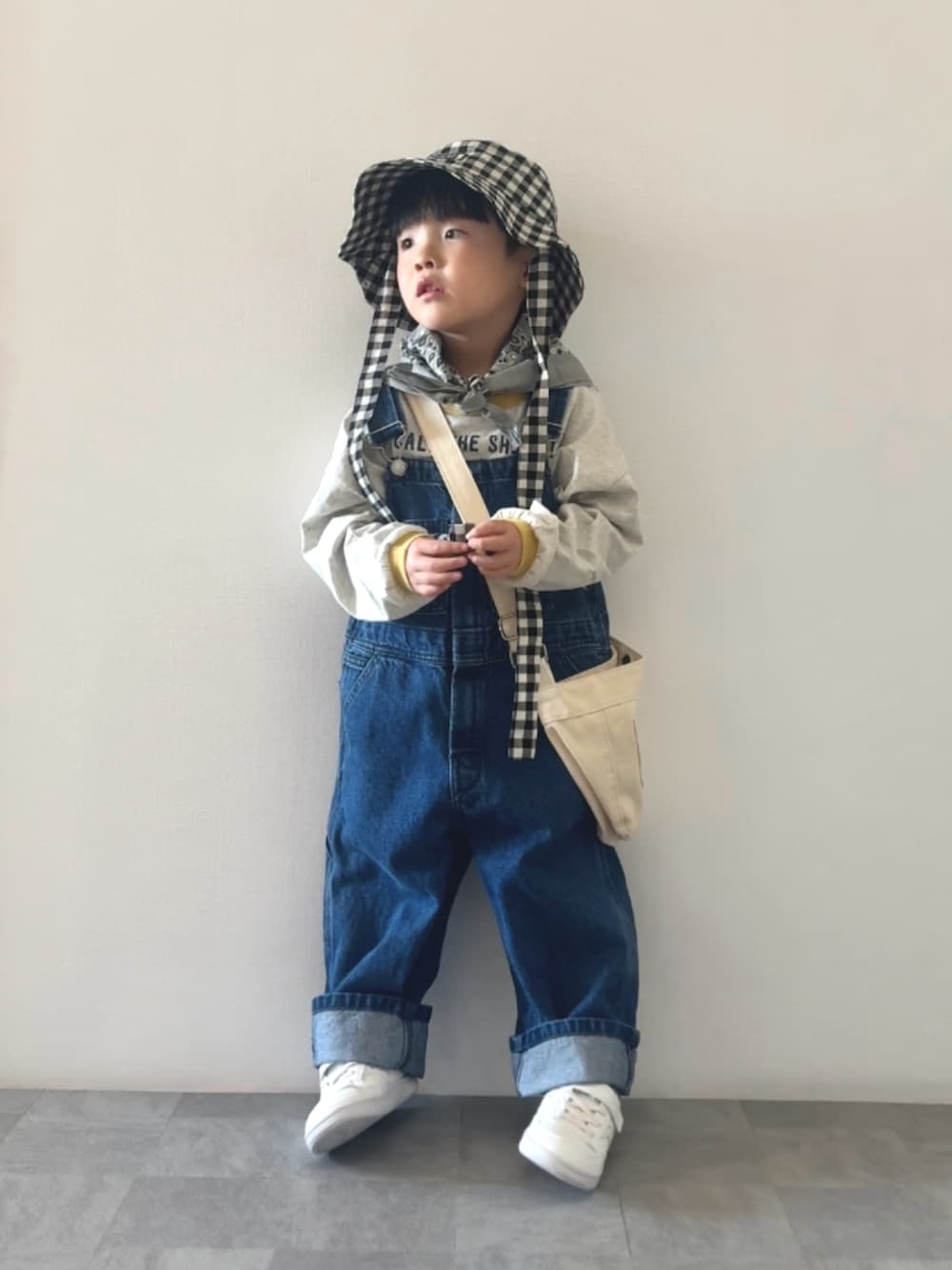 イエロー系のTシャツ/カットソー、ブルー系のサロペット/オーバーオール、ホワイト系のショルダーバッグを着用したキッズの冬コーディネートの2枚目の写真