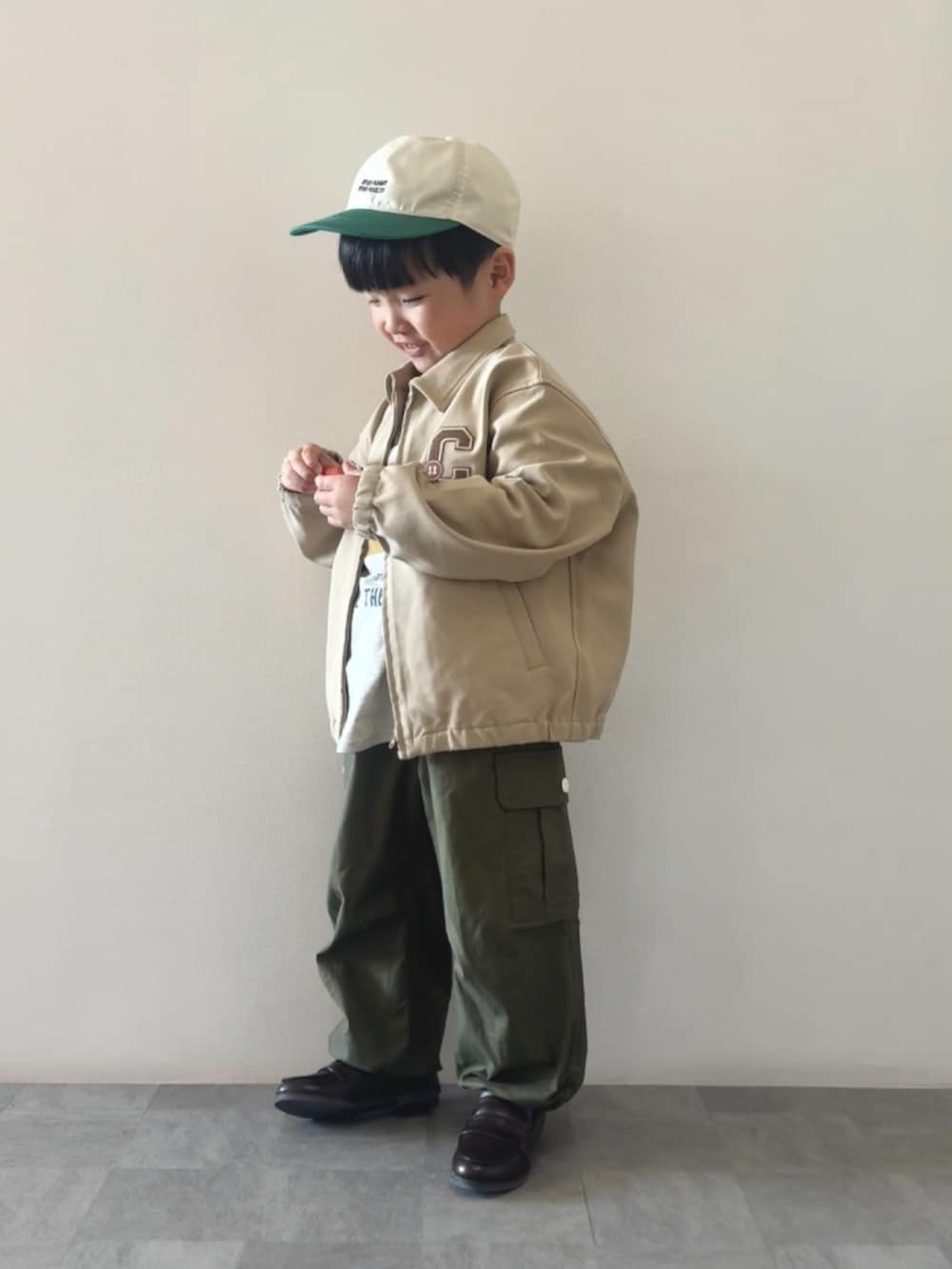 イエロー系のTシャツ/カットソー、ブラウン系のローファー、グリーン系のカーゴパンツを着用したキッズの冬コーディネートの2枚目の写真
