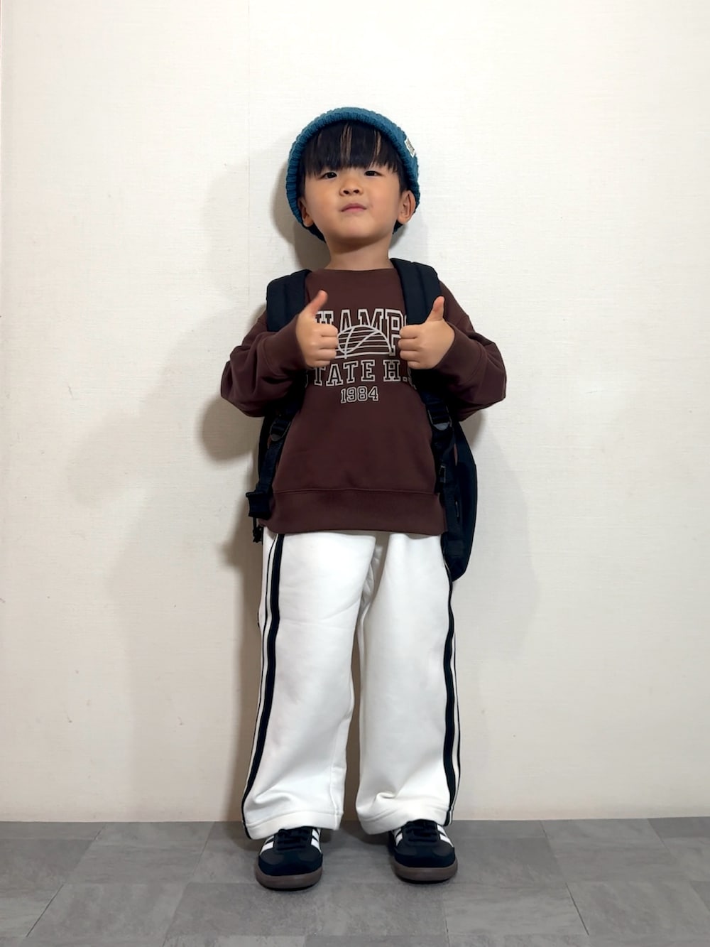 ブラック系のスニーカー、ブラック系のバックパック/リュック、ブラウン系のスウェットを着用したキッズの秋コーディネートの2枚目の写真
