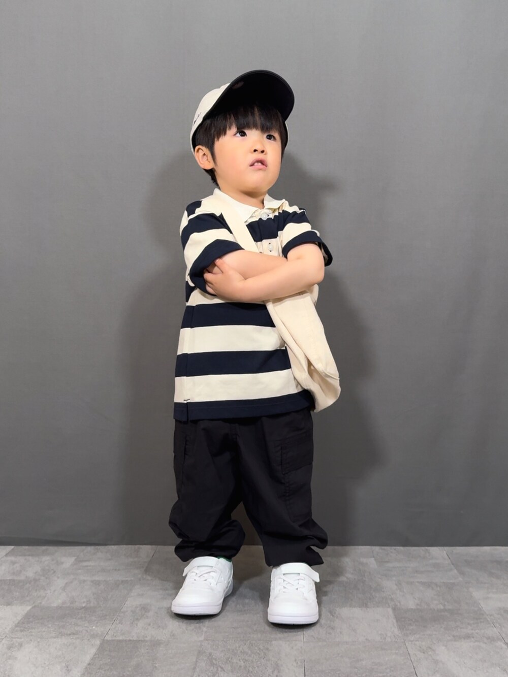 ベージュ系のトップス、ブラック系のパンツ、ホワイト系のショルダーバッグを着用したキッズの春コーディネートの2枚目の写真