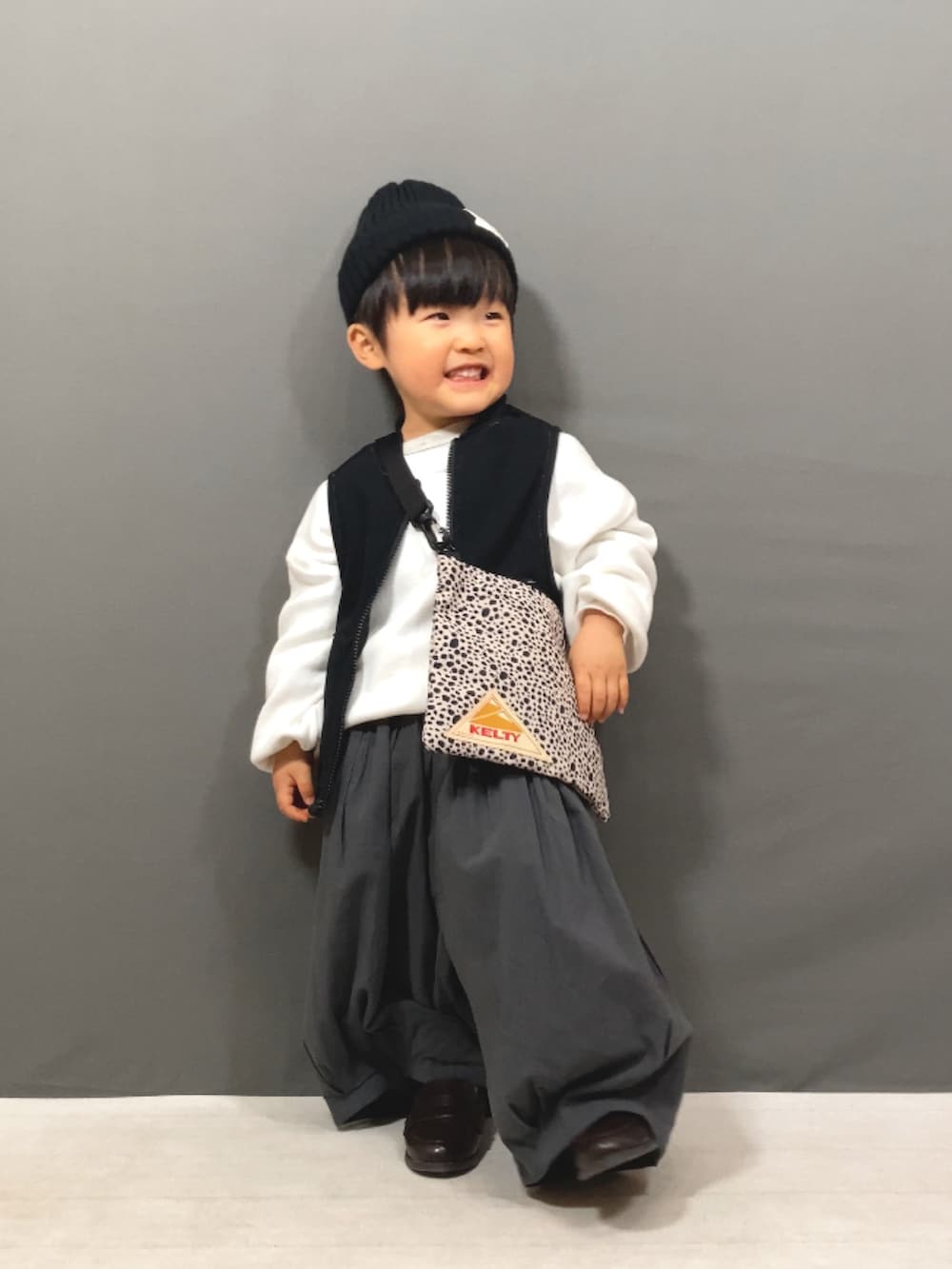 ホワイト系のニット/セーター、ブラック系のベスト、グレー系のその他パンツを着用したキッズの冬コーディネートの3枚目の写真