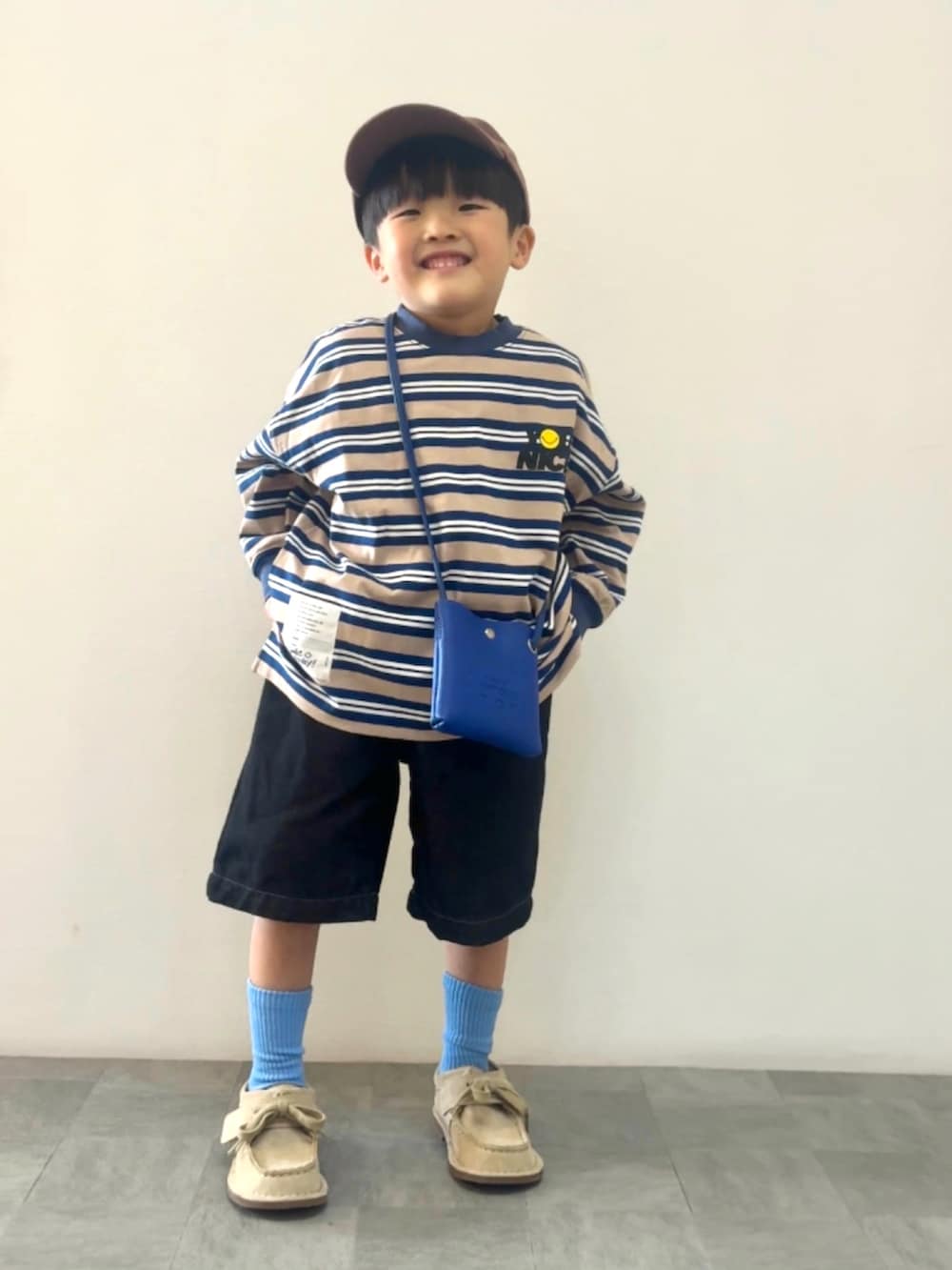 ブルー系のTシャツ/カットソー、ベージュ系のモカシン/デッキシューズ、ブルー系のショルダーバッグを着用したキッズの春コーディネートの2枚目の写真