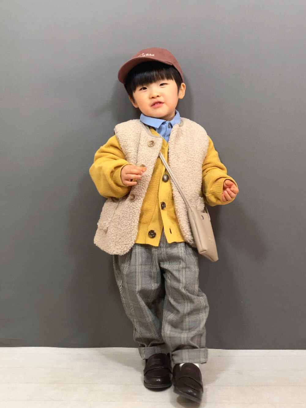 ベージュ系のベスト、イエロー系のカーディガン/ボレロ、ブルー系のシャツ/ブラウスを着用したキッズの冬コーディネートの4枚目の写真