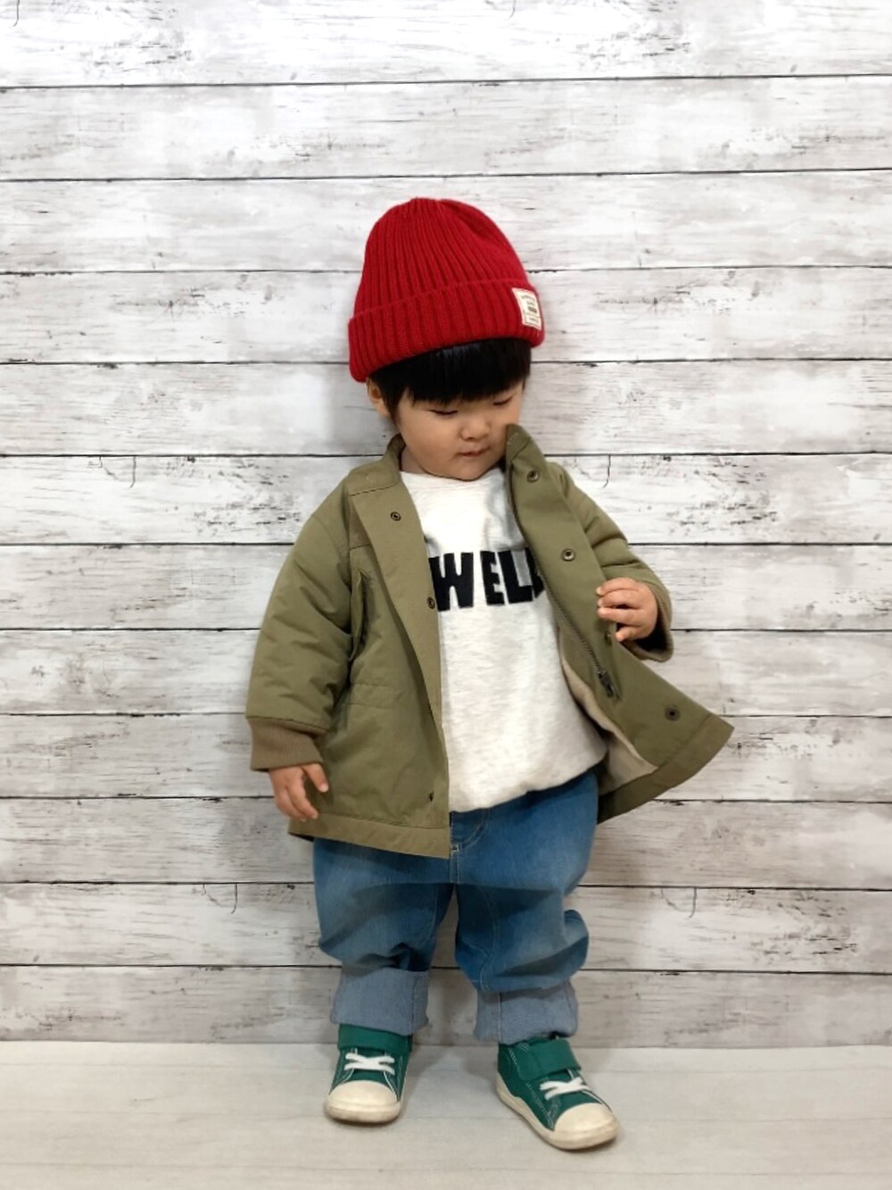 グリーン系のダウンジャケット/コート、グレー系のスウェット、ブルー系のデニムパンツを着用したキッズの秋コーディネートの2枚目の写真