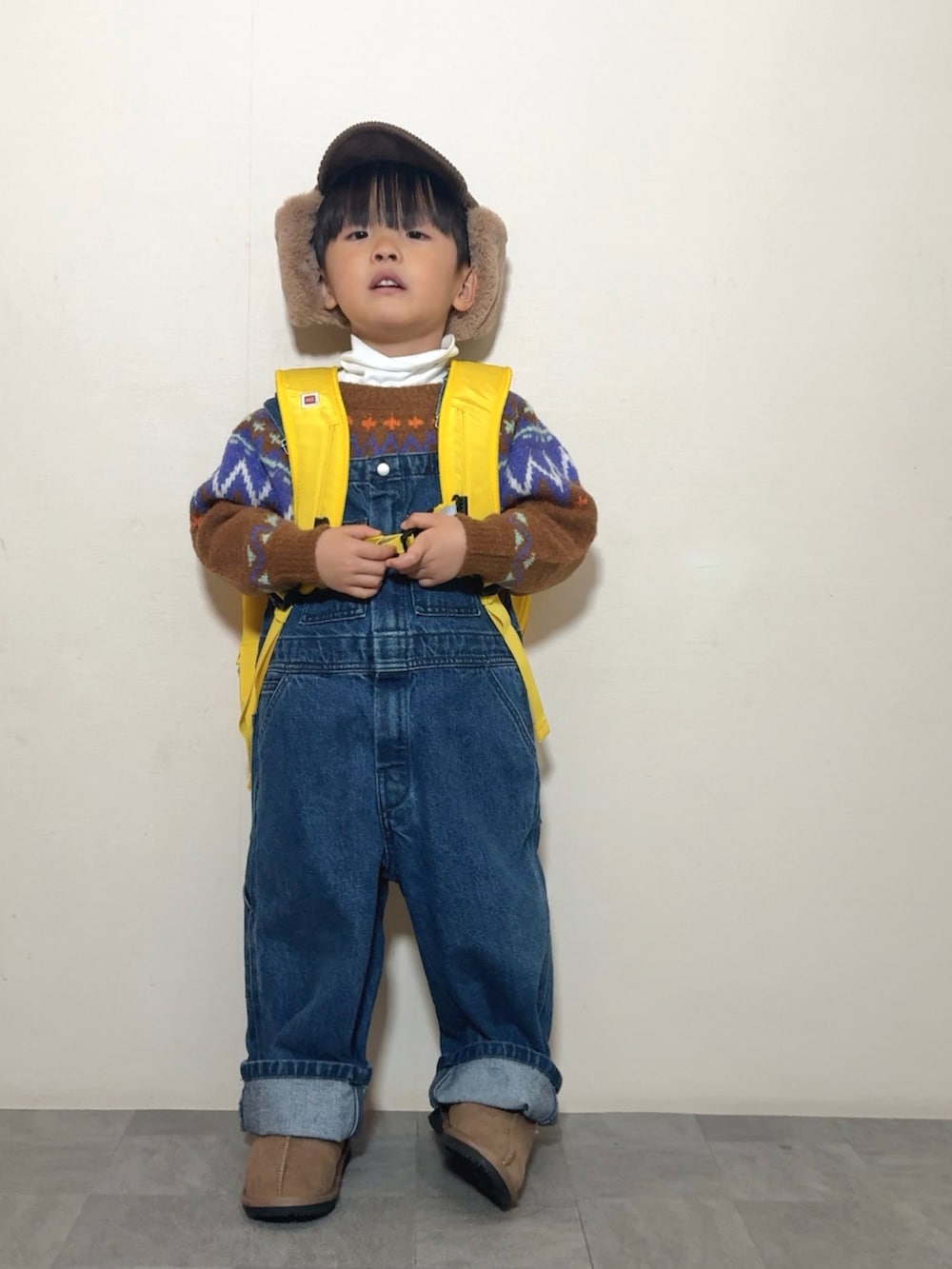 イエロー系のブーツ、イエロー系のバックパック/リュック、ブラウン系のニット/セーターを着用したキッズの冬コーディネートの3枚目の写真