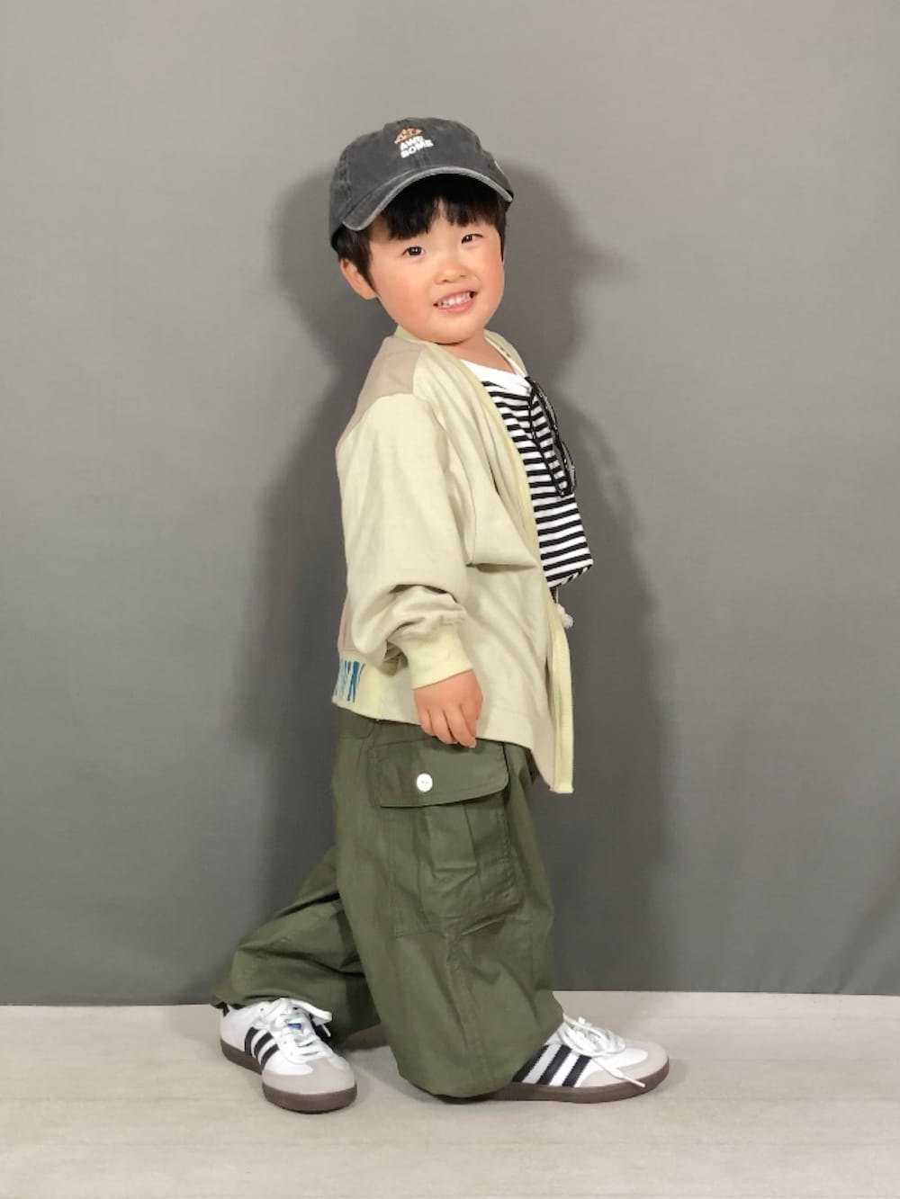 ベージュ系のカーディガン/ボレロ、ホワイト系のTシャツ/カットソー、グリーン系のカーゴパンツを着用したキッズの春コーディネートの2枚目の写真