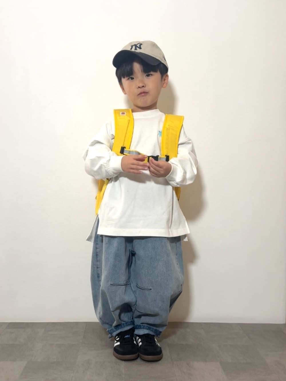 イエロー系のバックパック/リュック、ブラック系のスニーカー、ホワイト系のTシャツ/カットソーを着用したキッズの春コーディネートの3枚目の写真