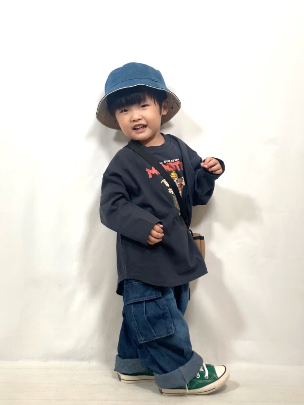 グレー系のトップス、ブルー系のデニムパンツ、イエロー系のショルダーバッグを着用したキッズの秋コーディネートの2枚目の写真