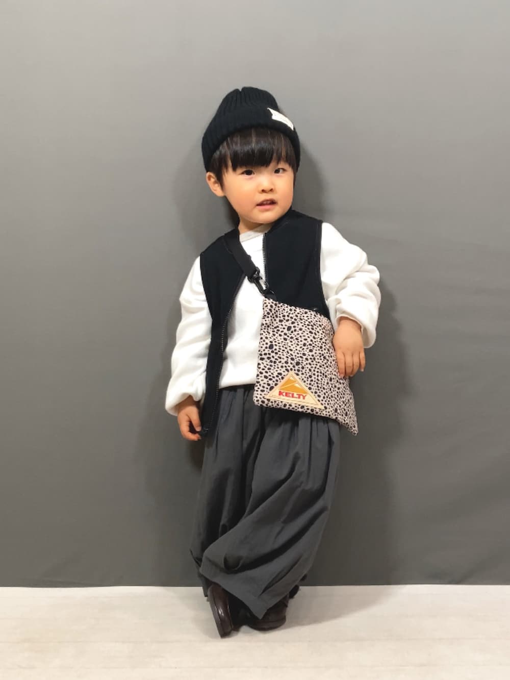 ホワイト系のニット/セーター、ブラック系のベスト、グレー系のその他パンツを着用したキッズの冬コーディネートの4枚目の写真