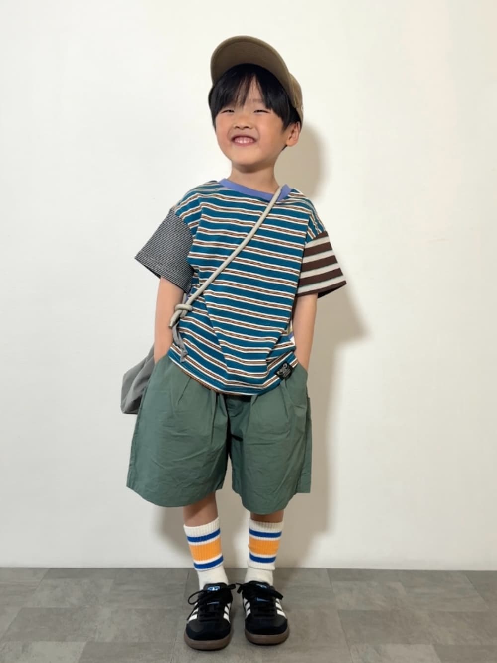 グレー系のショルダーバッグ、ブラック系のスニーカー、その他のTシャツ/カットソーを着用したキッズの春コーディネートの2枚目の写真