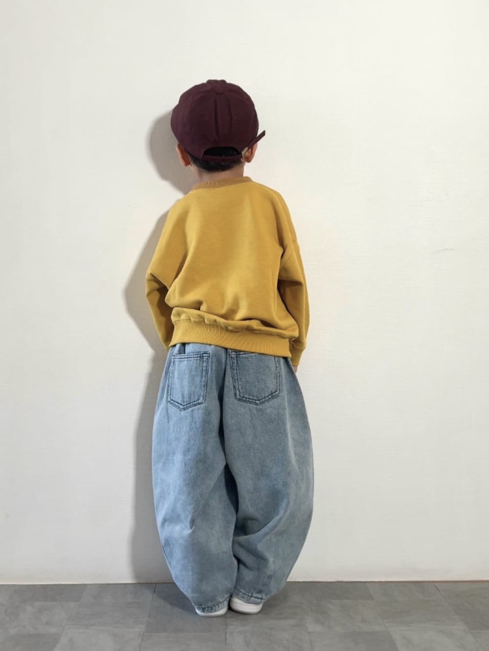ブルー系のデニムパンツ、ホワイト系のスニーカー、イエロー系のスウェットを着用したキッズの秋コーディネートの4枚目の写真