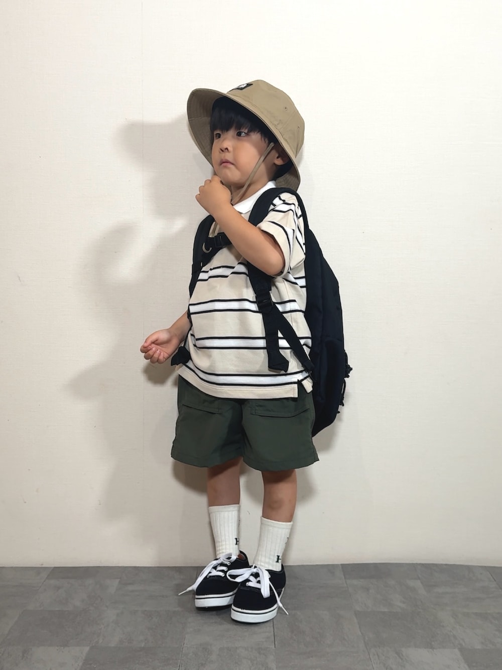 ベージュ系のポロシャツ、イエロー系のパンツ、ブラック系のバックパック/リュックを着用したキッズの夏コーディネートの2枚目の写真