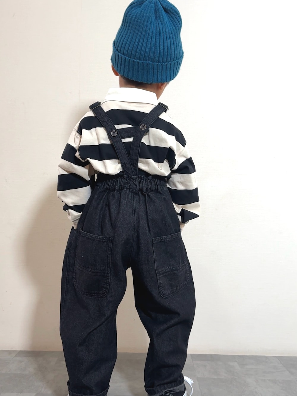 ブラック系のスニーカー、ブラック系のサロペット/オーバーオール、ホワイト系のポロシャツを着用したキッズの秋コーディネートの3枚目の写真