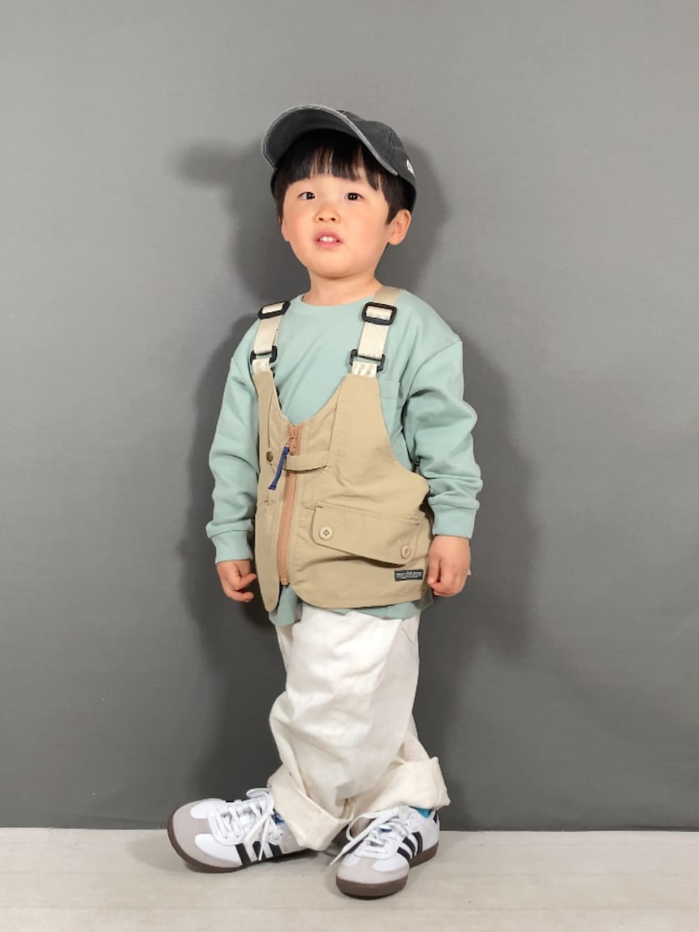 ベージュ系のベスト、グリーン系のTシャツ/カットソー、ホワイト系のパンツを着用したキッズの春コーディネートの5枚目の写真