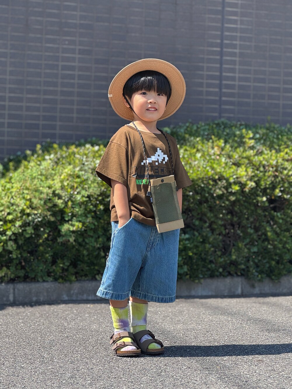 ブラウン系のサンダル、ベージュ系のショルダーバッグ、ブラウン系のTシャツ/カットソーを着用したキッズの夏コーディネートの2枚目の写真