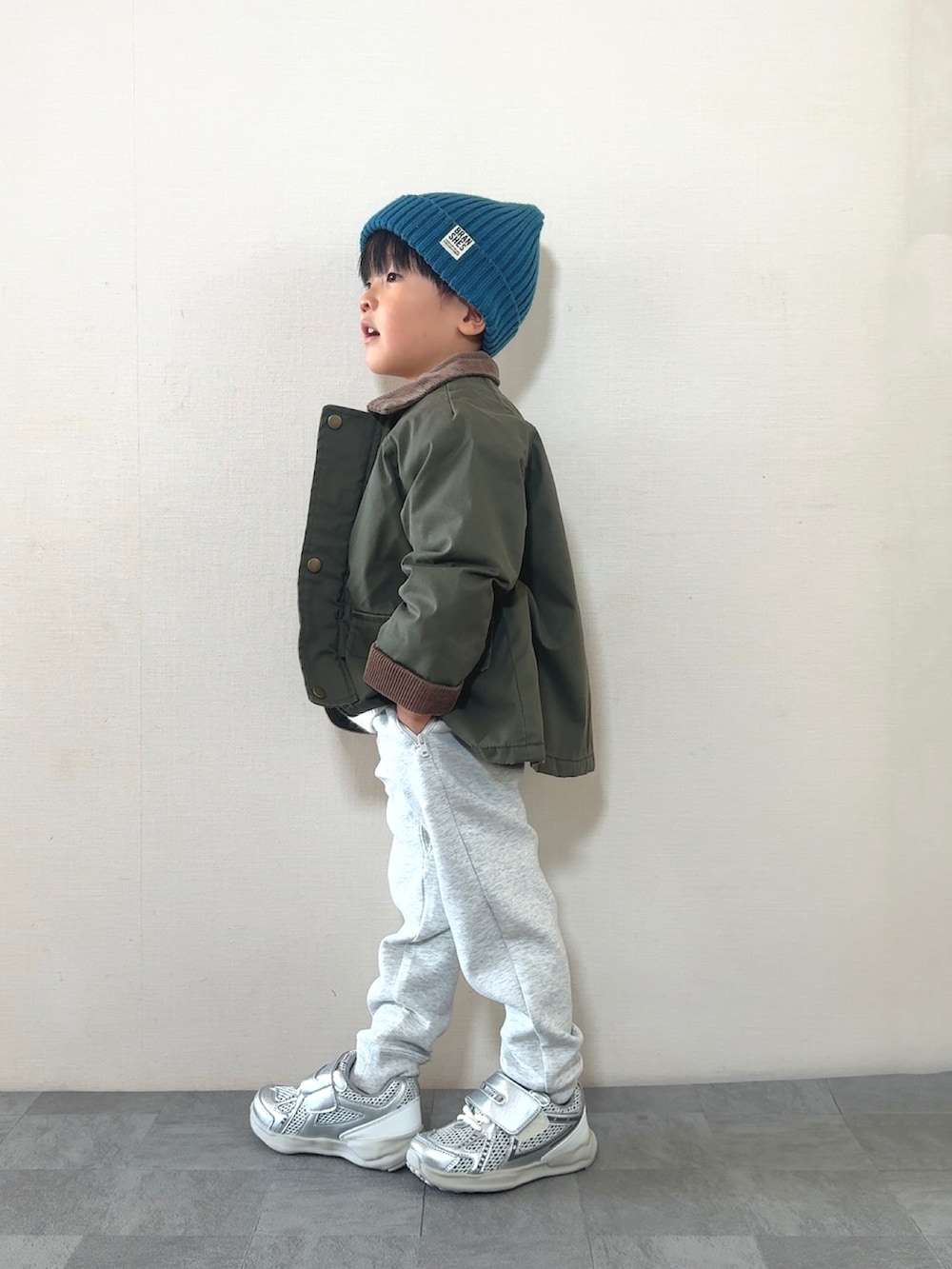 シルバー系のスニーカー、ホワイト系のニット/セーター、グリーン系のジャケット/アウターを着用したキッズの秋コーディネートの3枚目の写真