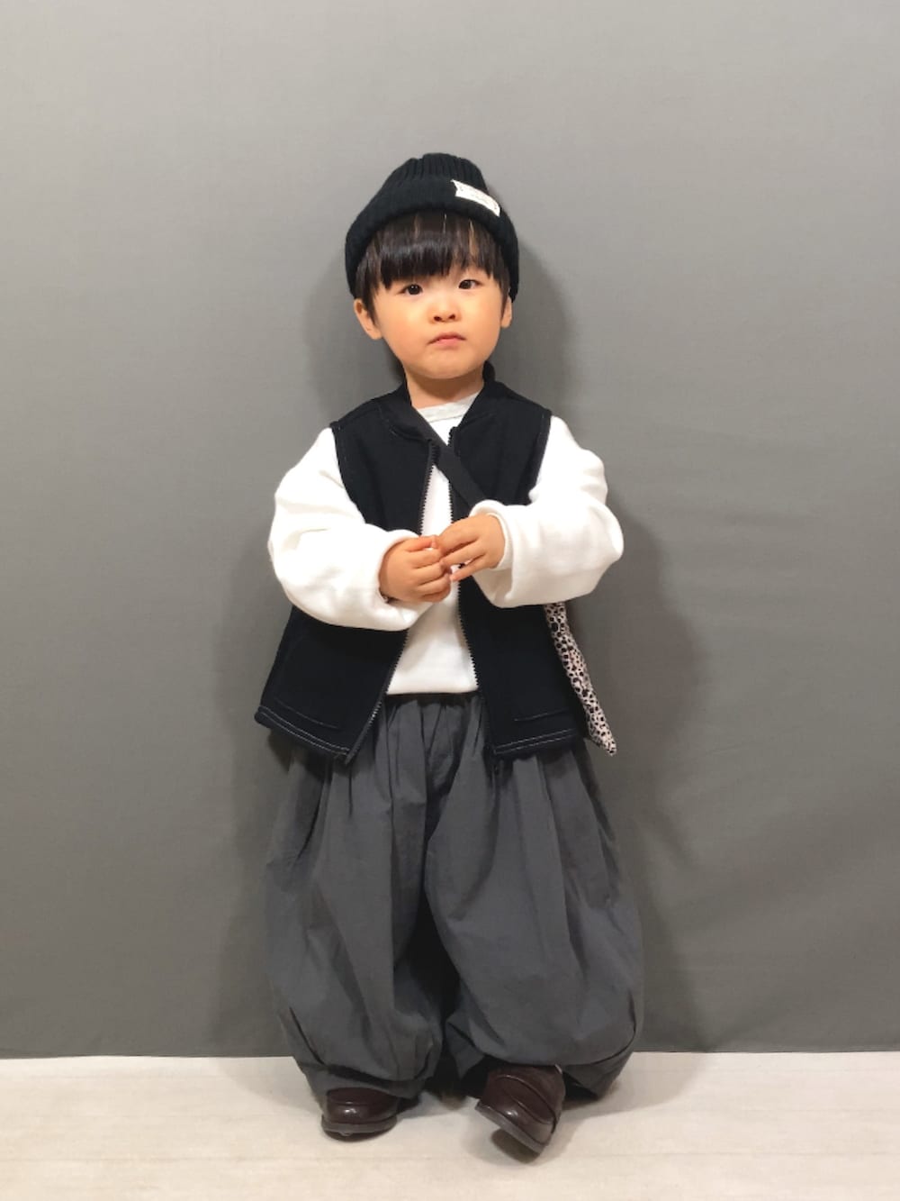 ホワイト系のニット/セーター、ブラック系のベスト、グレー系のその他パンツを着用したキッズの冬コーディネートの5枚目の写真
