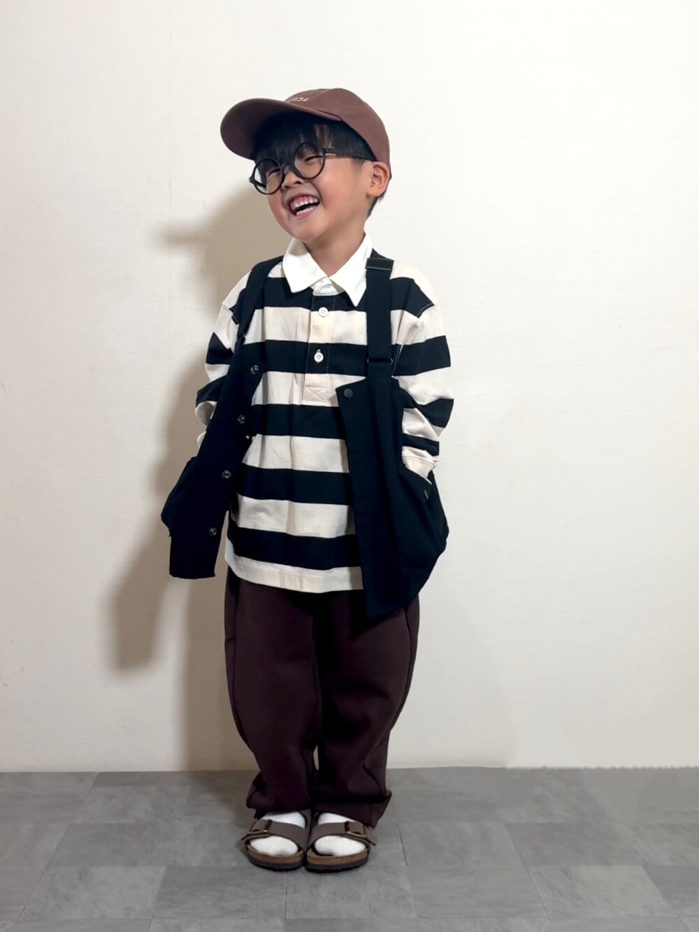 ブラウン系のサンダル、ブラック系のベスト、ホワイト系のポロシャツを着用したキッズの夏コーディネートの4枚目の写真