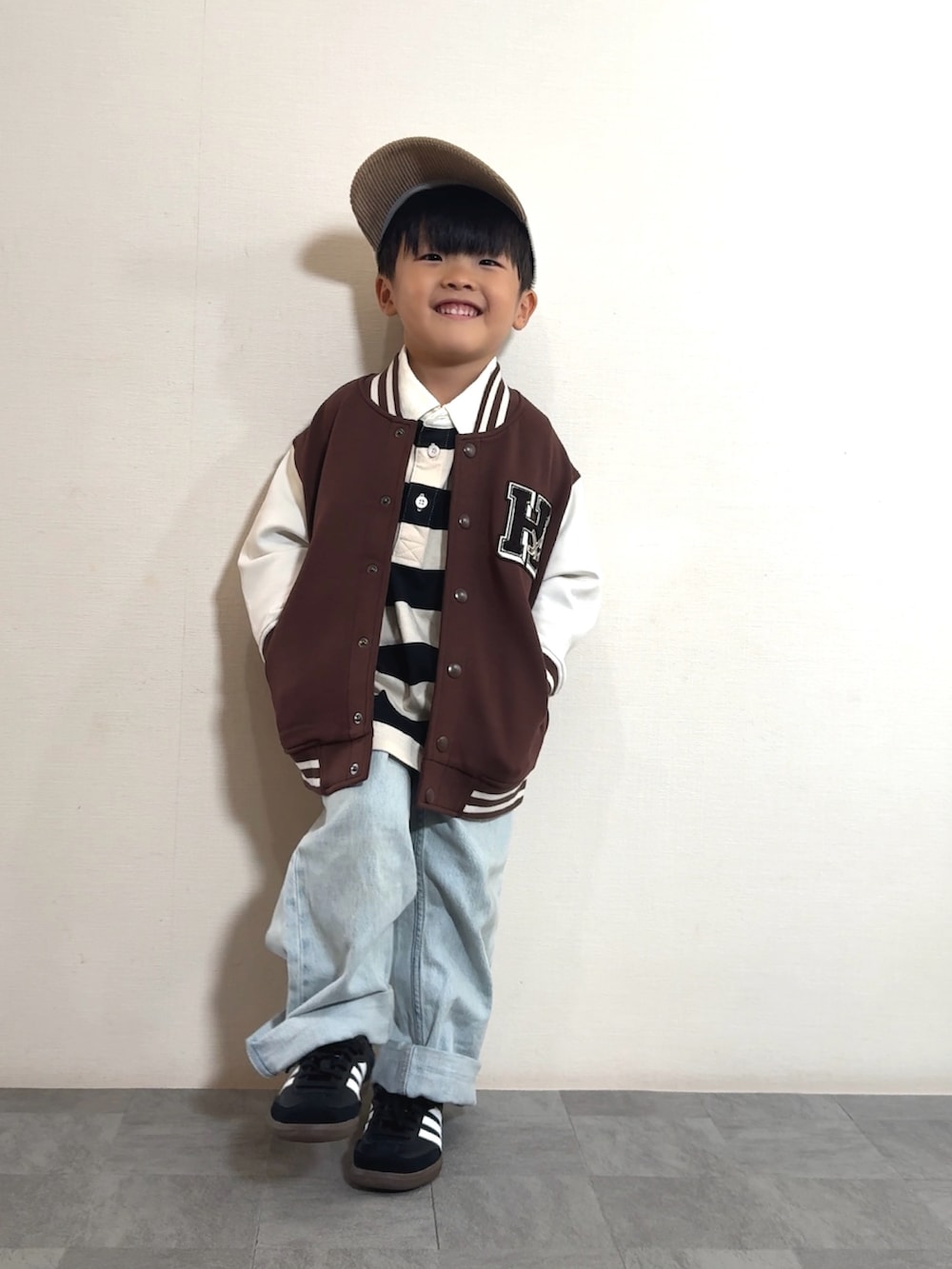 ブラック系のスニーカー、ホワイト系のポロシャツ、ブラウン系のスタジャンを着用したキッズの秋コーディネートの2枚目の写真