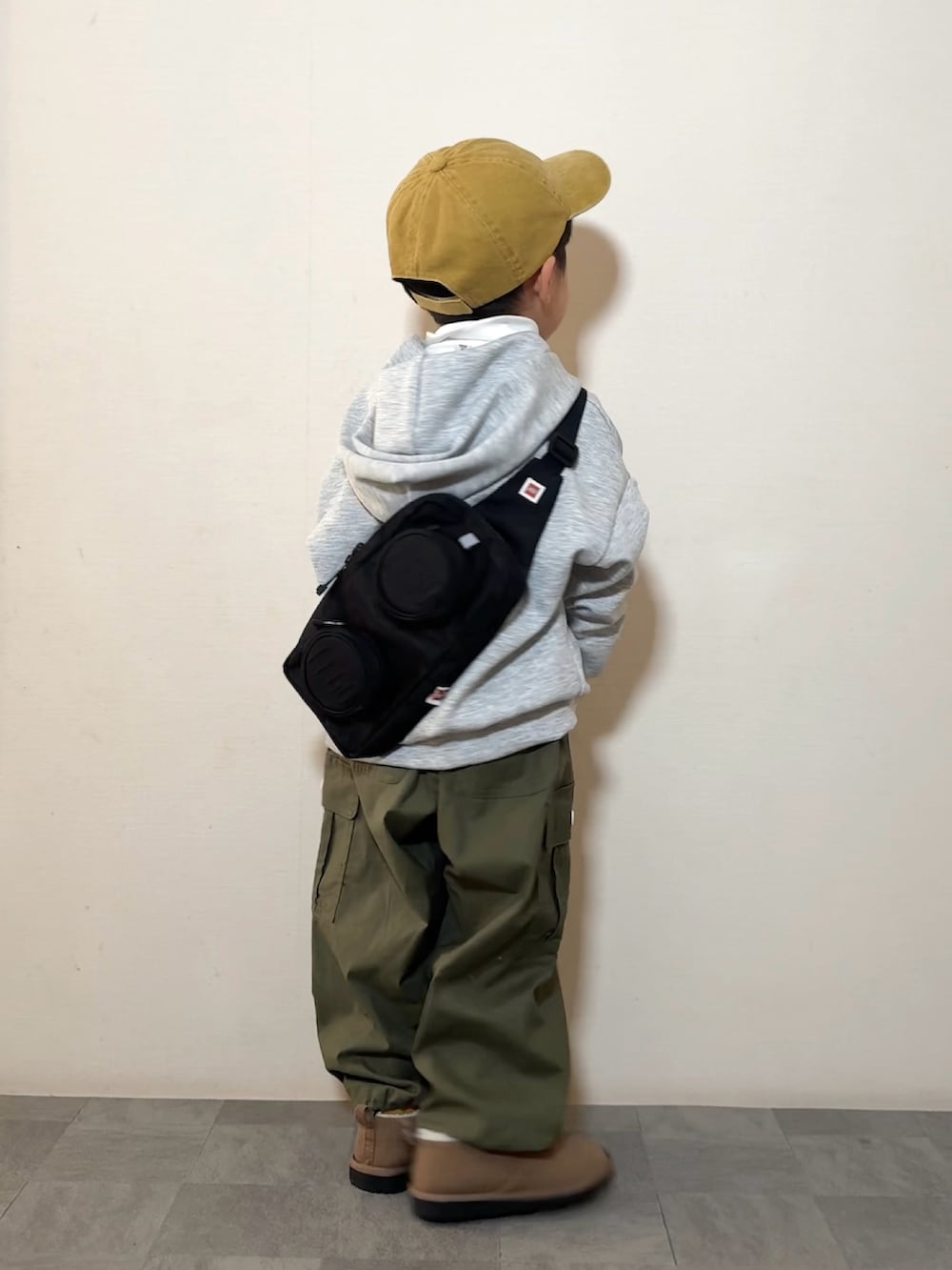 イエロー系のブーツ、ホワイト系のTシャツ/カットソー、グリーン系のカーゴパンツを着用したキッズの冬コーディネートの2枚目の写真