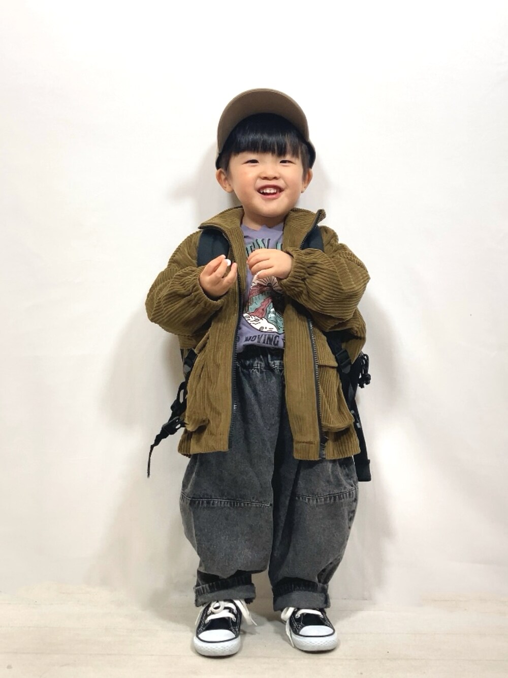 グリーン系のブルゾン、パープル系のTシャツ/カットソー、ブラック系のデニムパンツを着用したキッズの冬コーディネートの3枚目の写真