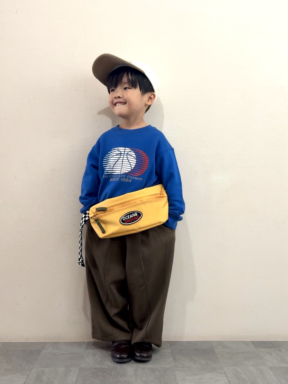 ブラウン系のスラックス、ブラウン系のローファー、ブルー系のスウェットを着用したキッズの秋コーディネートの2枚目の写真