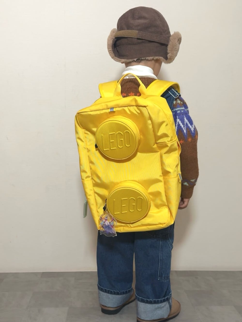 イエロー系のブーツ、イエロー系のバックパック/リュック、ブラウン系のニット/セーターを着用したキッズの冬コーディネートの5枚目の写真