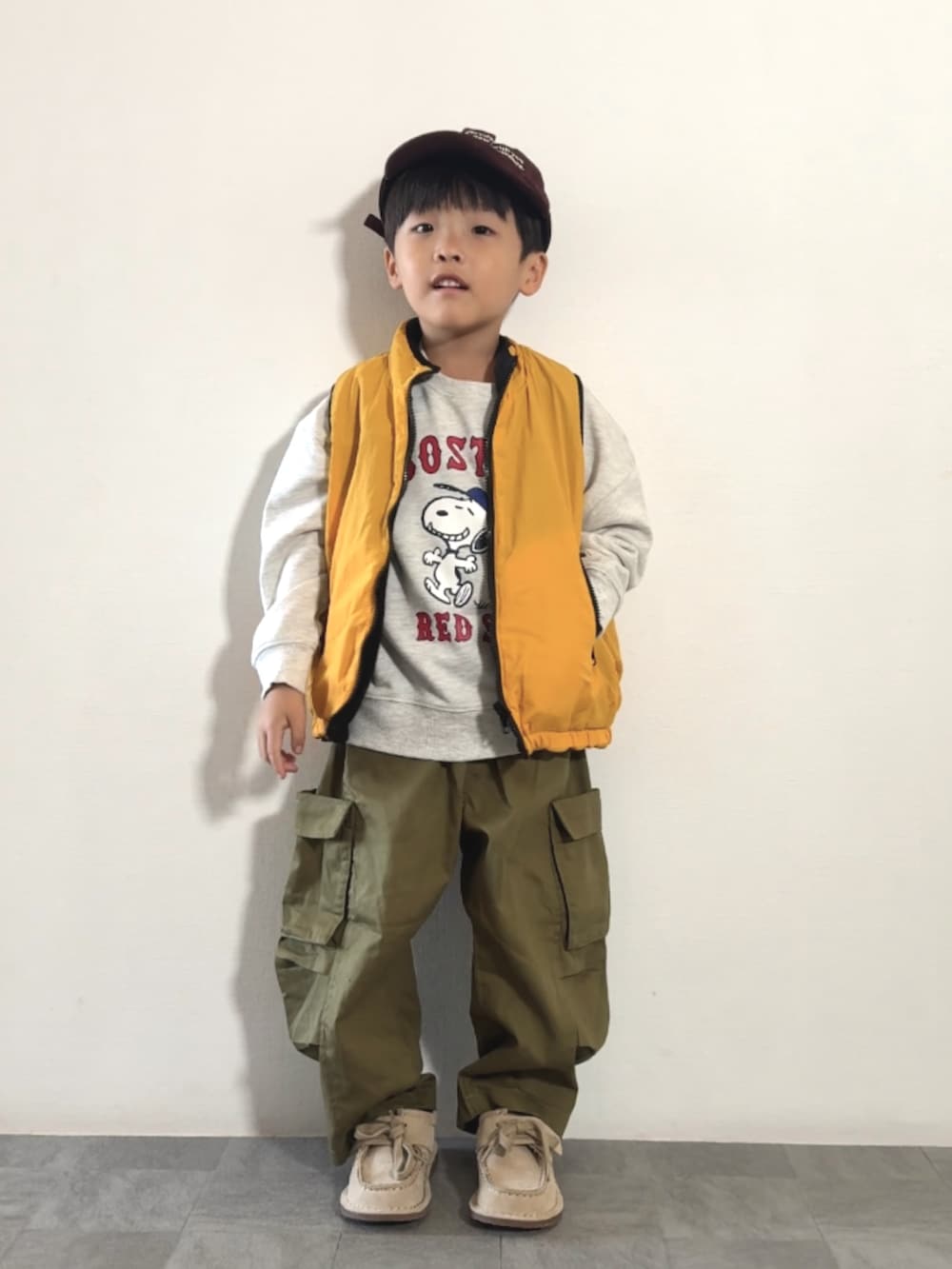 イエロー系のベスト、ベージュ系のモカシン/デッキシューズ、グリーン系のカーゴパンツを着用したキッズの秋コーディネートの2枚目の写真